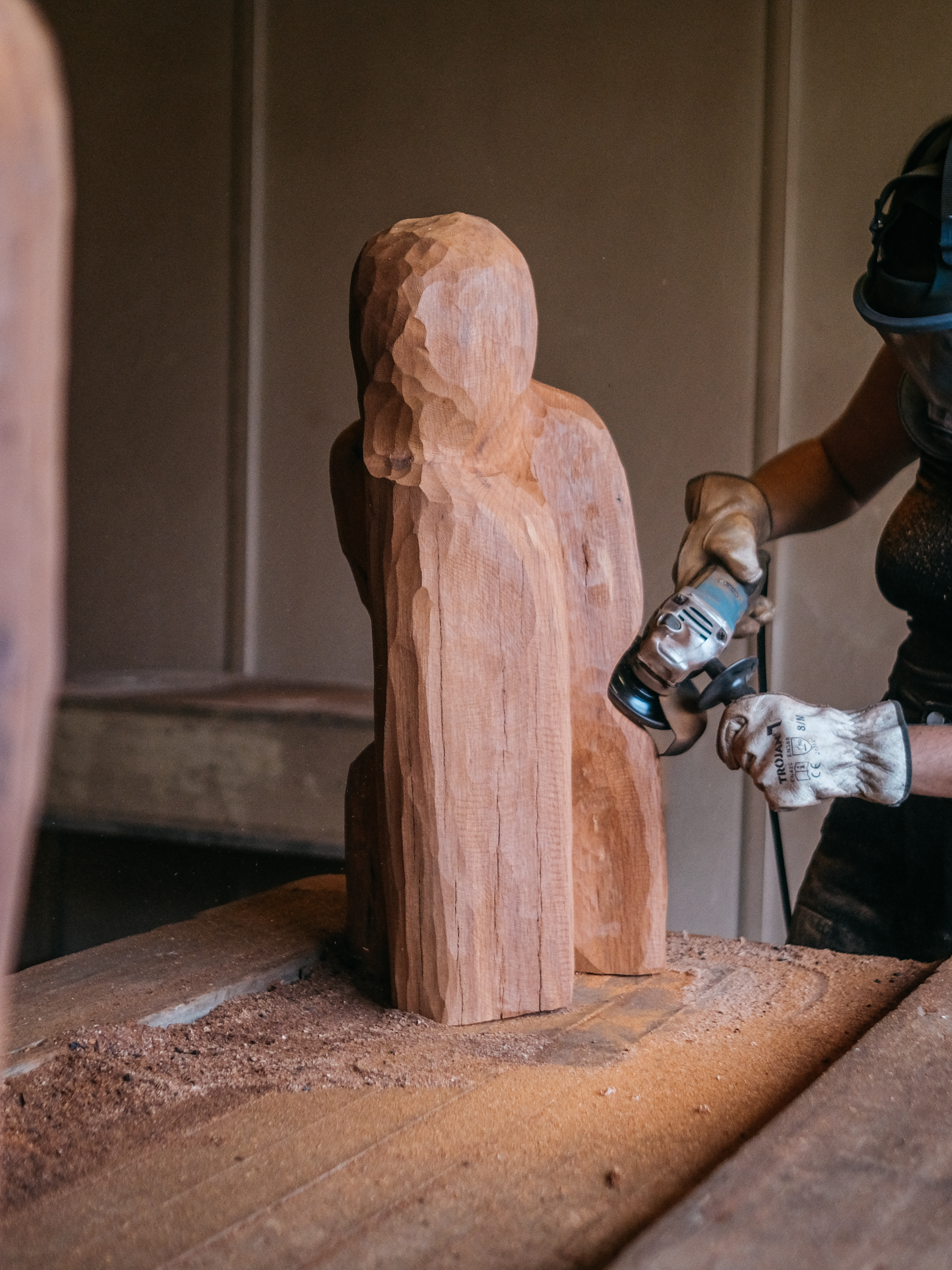 The artist uses a carving tool to shape a medium-sized piece of wood