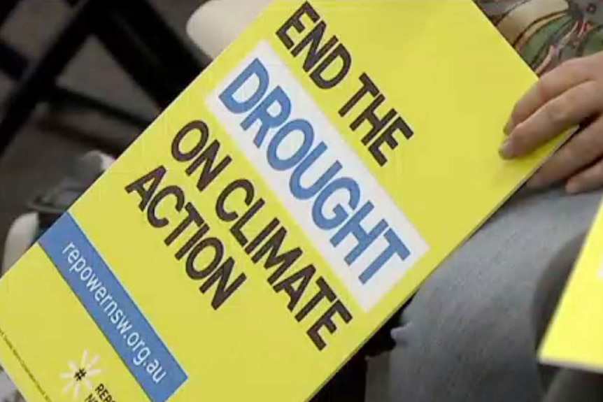 A man holds a yellow sign saying 'end the drought on climate action'