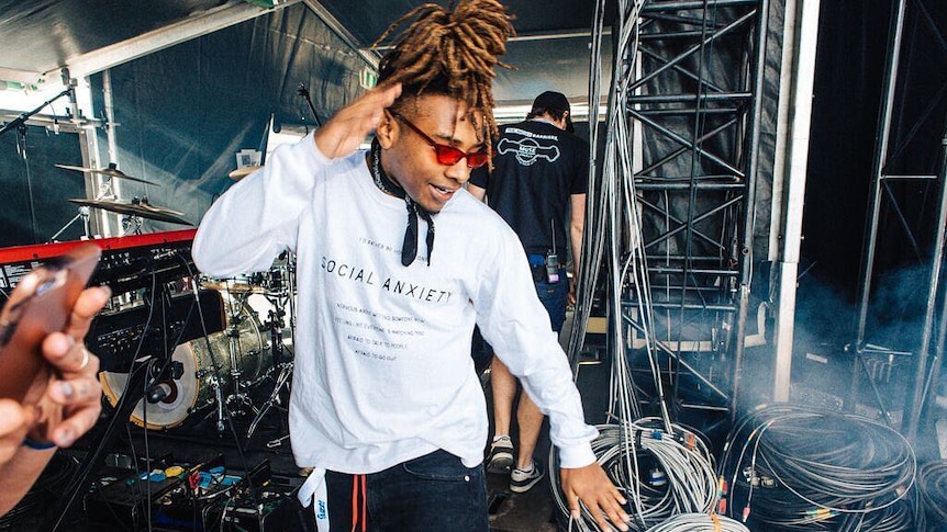 A dreadlocked man is dancing on stage.