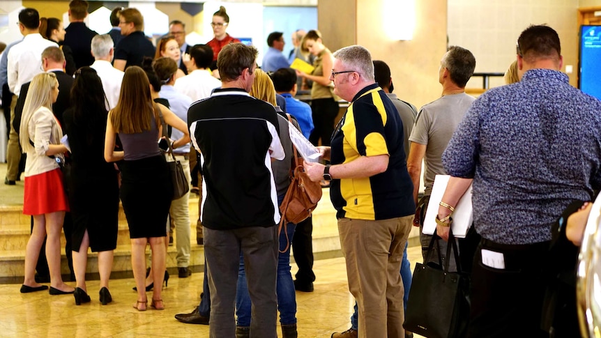 A line of people snakes through the foyer of a building.