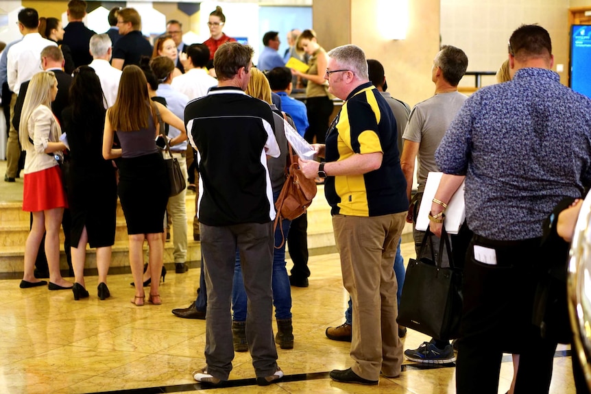 A line of people snakes through the foyer of a building.