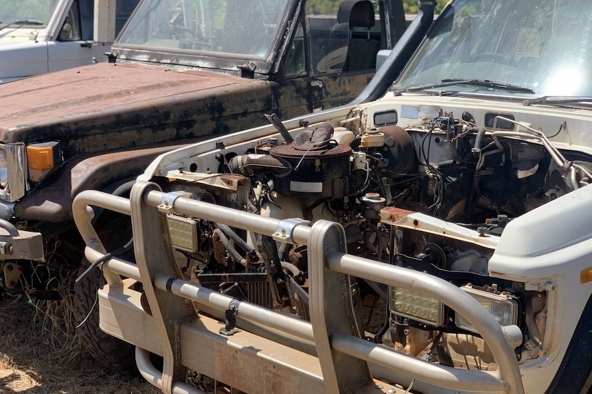 A beaten-up-looking four-wheel drive with its bonnet missing.