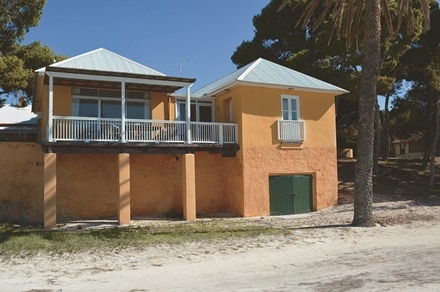 A brick cottage with a balcony that overlooks a beach.