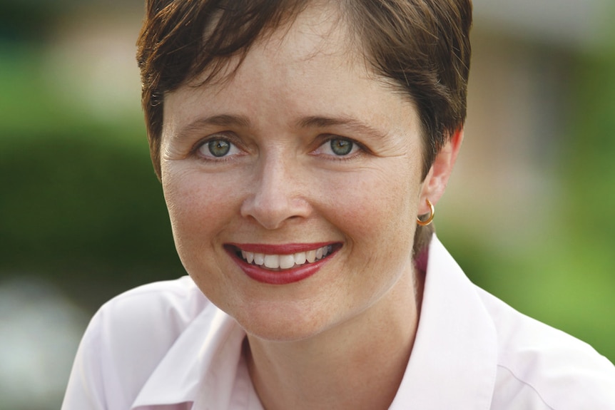 A woman with short hair smiles at the camera.