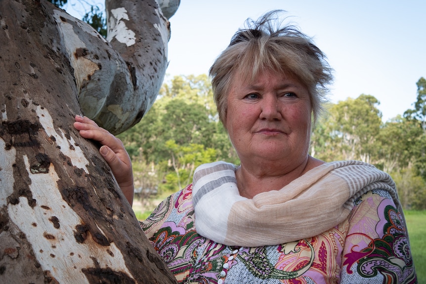 woman leans on tree