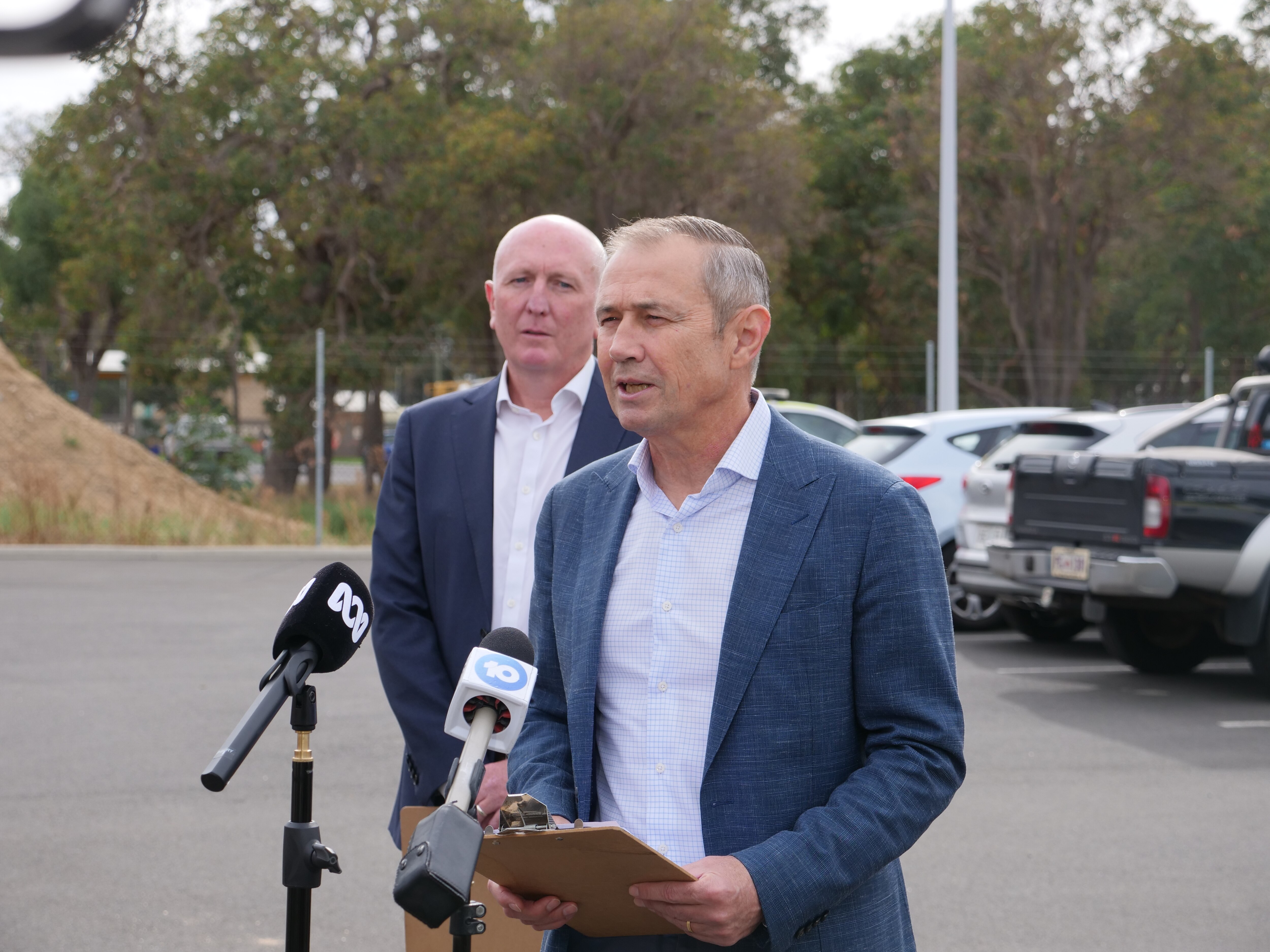 Several people speak to the media outside.