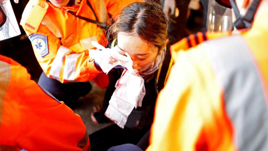 A medic attends to a young woman with an injured eye.