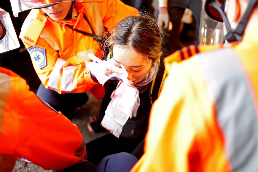 A medic attends to a young woman with an injured eye.