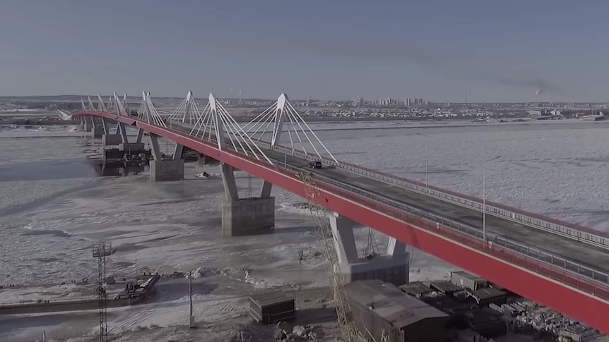 A large road bridge stretches over icy water.