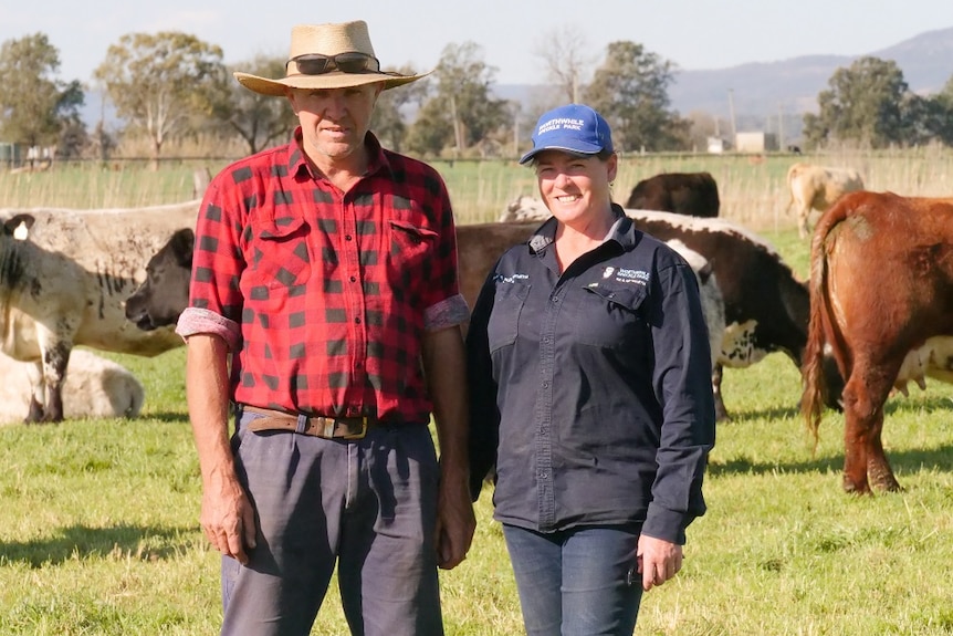 Robert and Narelle Worth stand in a paddock in front of their cows.
