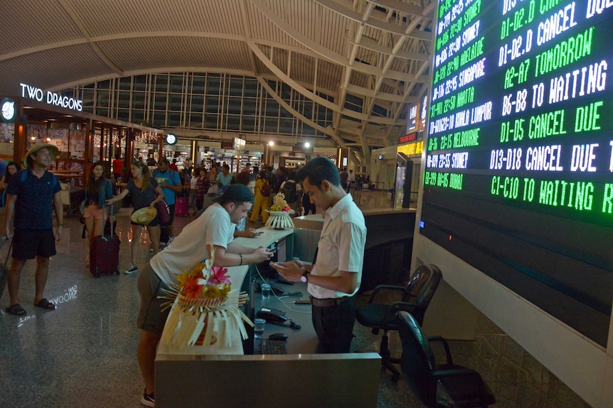 Passengers wait for flight information inside the Nguarah Rai airport terminal.