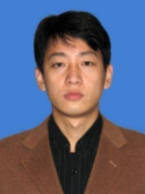 Headshot of an Asian man wearing a brown jacket and black shirt.