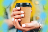 A pair of hands, with pale painted nails, holding a brown coffee cup with green and yellow artistic swirls around it