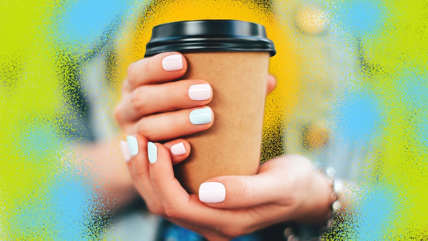 A pair of hands, with pale painted nails, holding a brown coffee cup with green and yellow artistic swirls around it