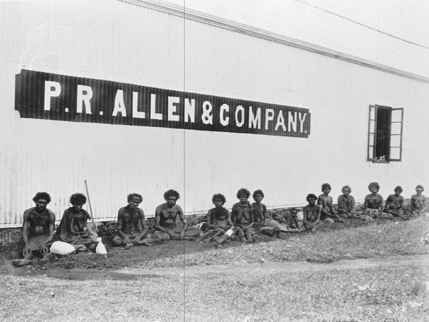 A group of Aboriginal people sit in front of a building with sign 'P R Allen & Company'