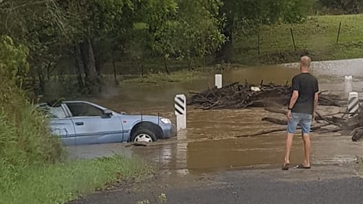 A blue car partly submerged in floodwaters on Randwick Road near Tin Can Bay Road in Gympie