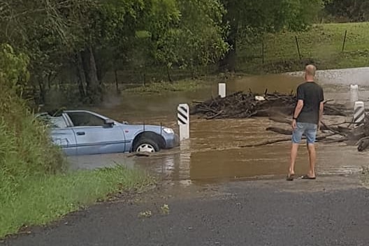 A blue car partly submerged in floodwaters on Randwick Road near Tin Can Bay Road in Gympie