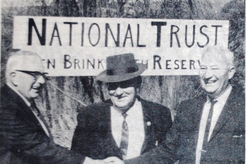 Black and white photograph of three men in front of National trust sign circa 1960s
