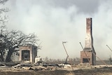 The smouldering ruin of a house destroyed by a wildfire.