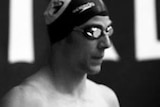A black and white photo of a swimmer wearing a cap and goggles.