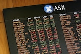 Investors watch the share price indicator board at the Australian Stock Exchange