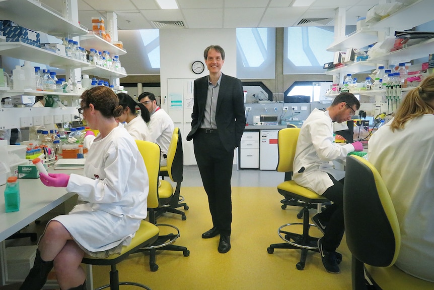 Rufus Black stands in centre of science lab, surrounded by students.