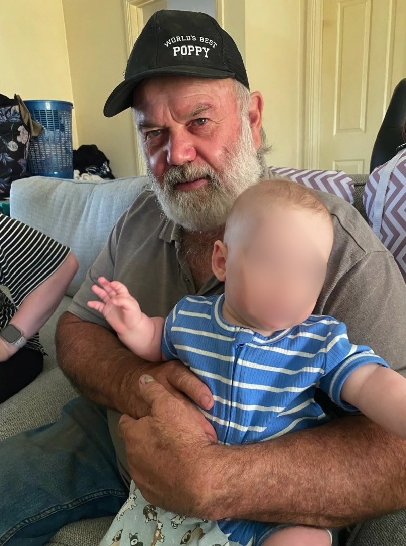 Man wearing black cap holding a baby
