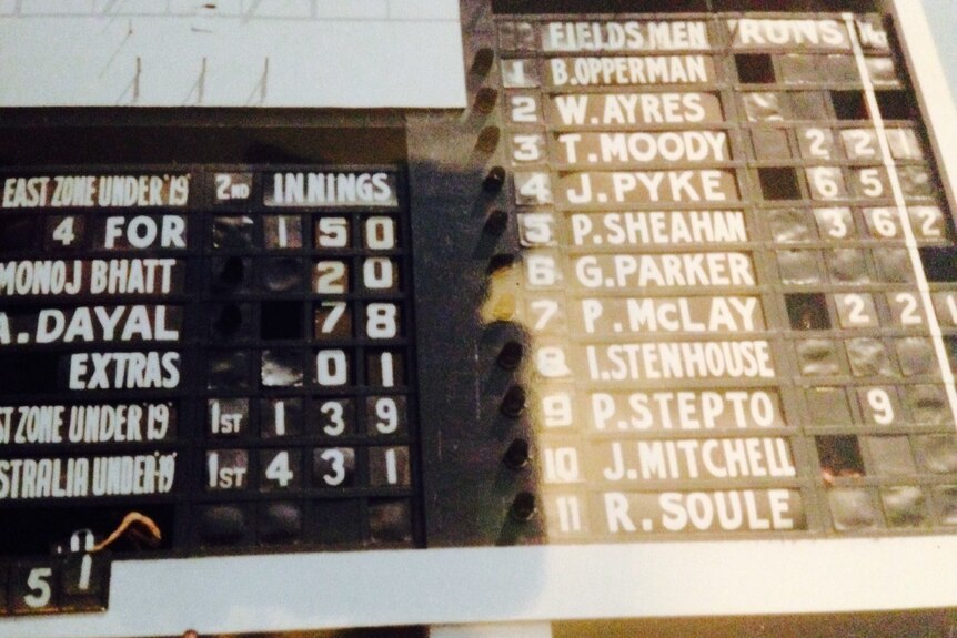A traditional cricket scoreboard displays match figures for a game.