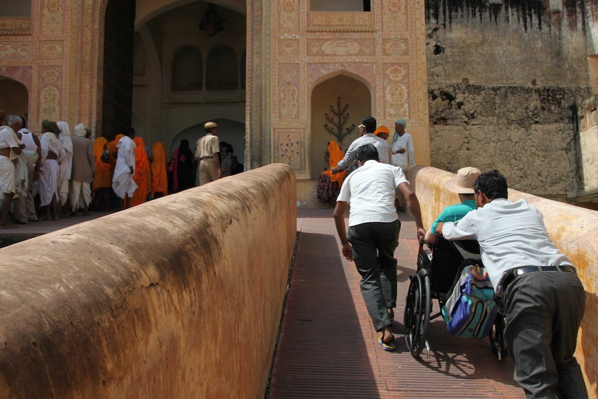 Men pushing Martin in his wheelchair.