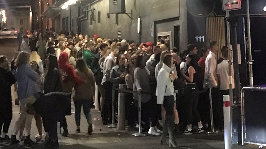 A large line-up of people in an alley-way