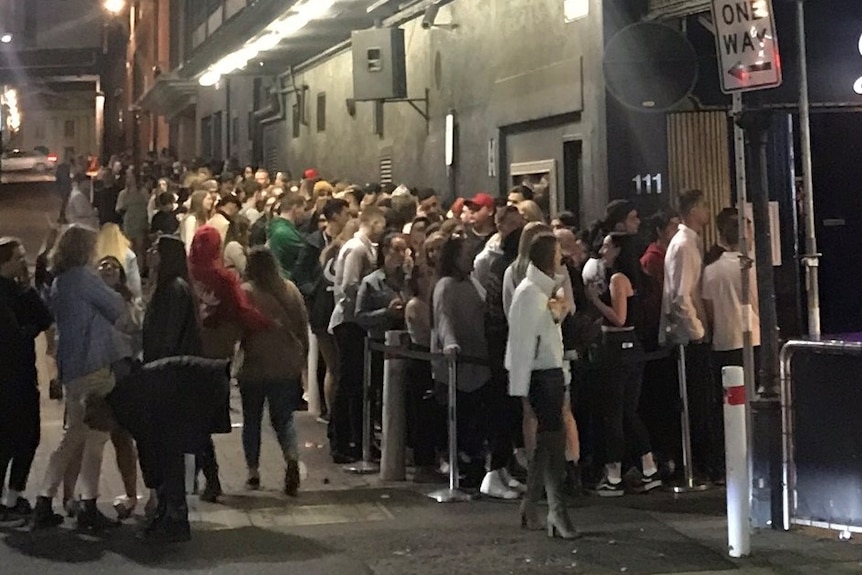 A large line-up of people in an alley-way