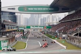 Formula One cars run down the straight before a Grand Prix in China, as fans pack the grandstands.