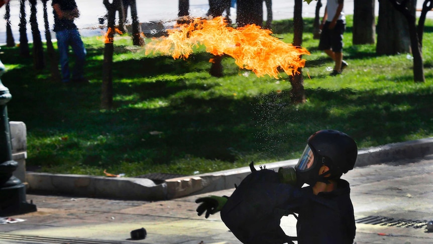A protester throws a petrol bomb at riot police during clashes in Athens