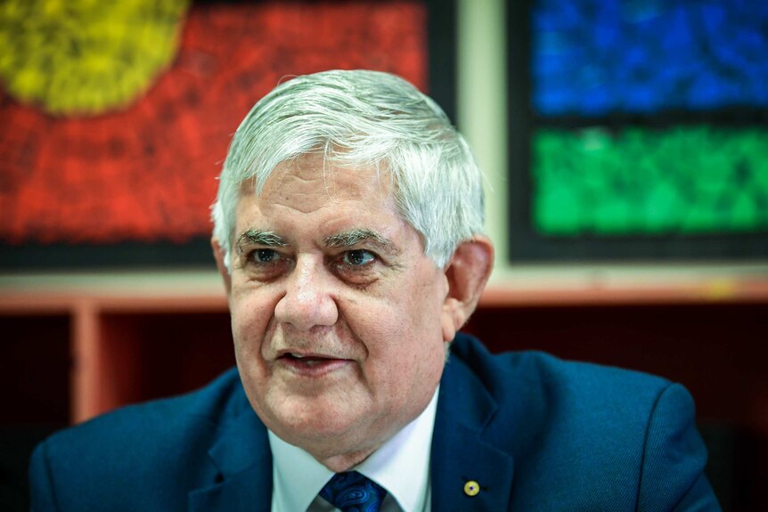 Ken Wyatt with Aboriginal and Torres Straight flags in the background