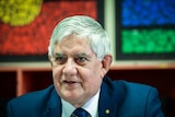 Ken Wyatt with Aboriginal and Torres Straight flags in the background