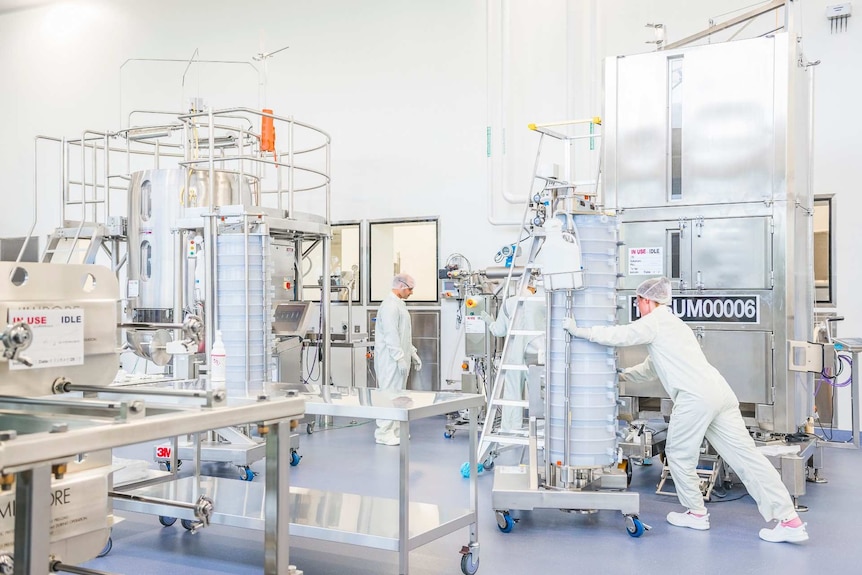 People in white lab coats and hairnets in a room with stainless steel laboratory equipment