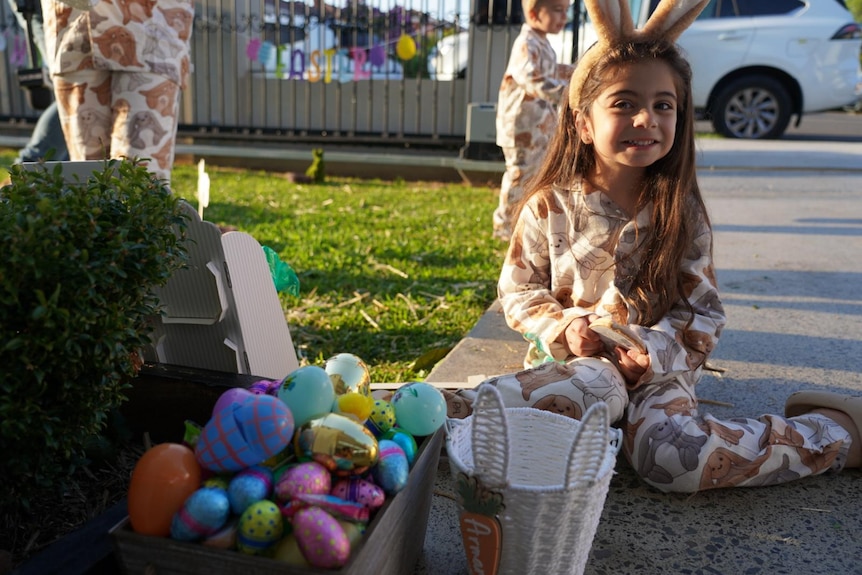 A young girl sitting with a basket of easter eggs
