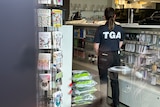 A woman in a TGA shirt is seen standing guard inside a pharmacy