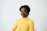Head and shoulders shot of a woman with dark skin and black hair wearing a yellow jumper
