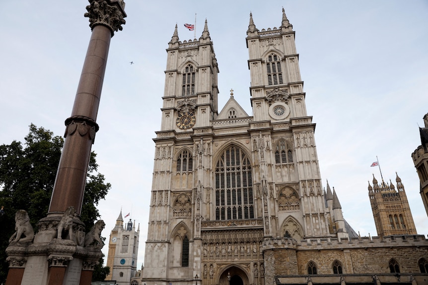 An ornate cathedral with flags flying at half mast.