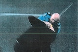 A still image taken from video footage showing a police officer wrestling with a man who is attacking him with a samurai sword.