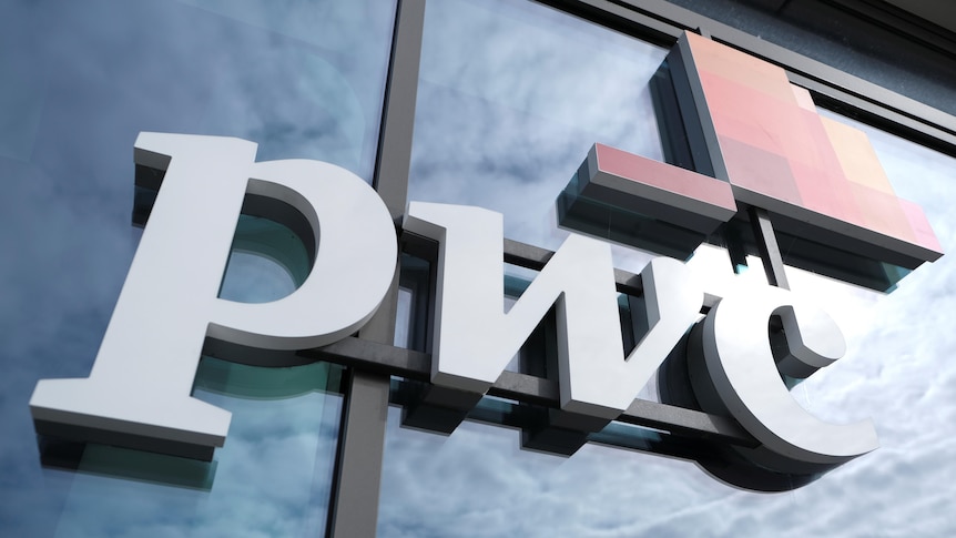 A close-up of a corporate pwc logo on a reflective glass building panel.