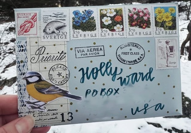 A hand holds a decorated letter.