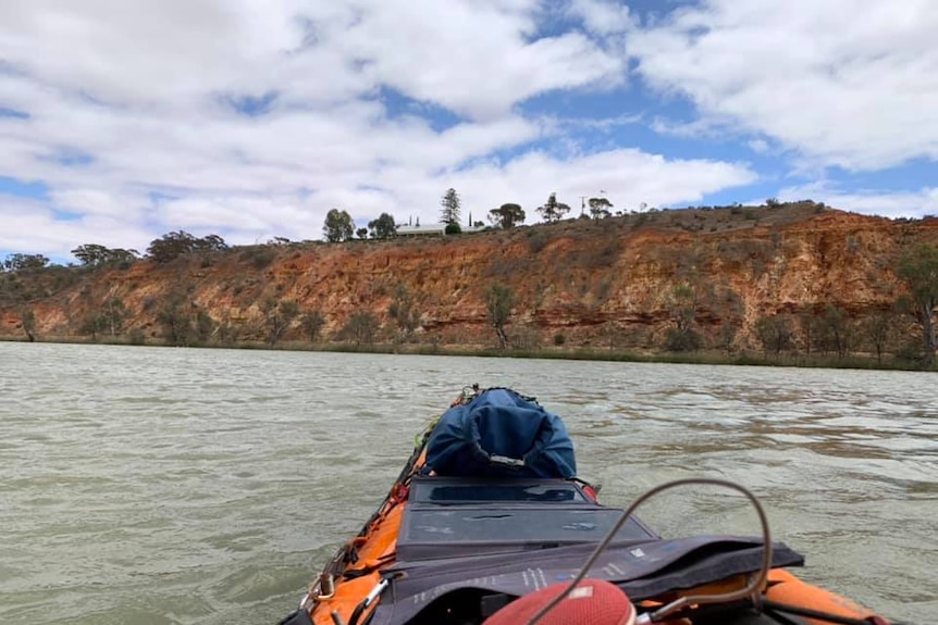 Cliffs along the River Murray looking over the front of a kayak.