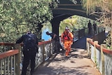 Police and SES workers check the Torrens and riverbanks the day after a body was pulled from the water