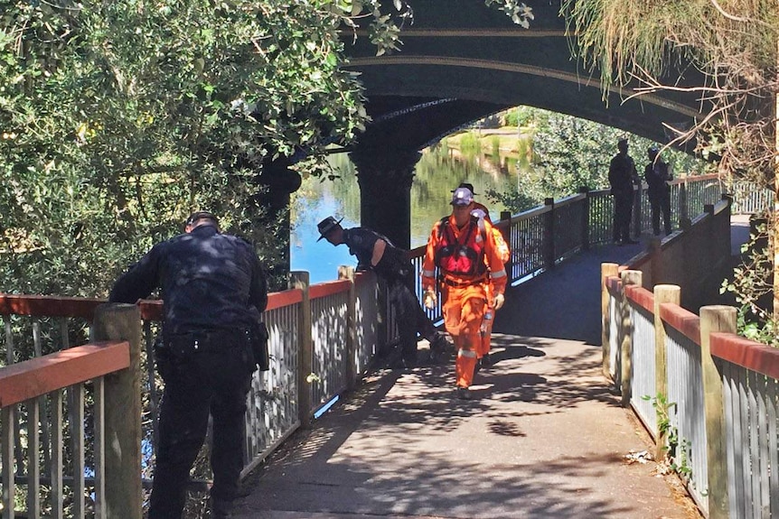 Police and SES workers check the Torrens and riverbanks the day after a body was pulled from the water