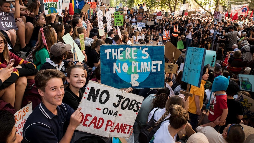 Protesters in Adelaide hold signs that say "No jobs on a dead planet" and "There's no planet B".