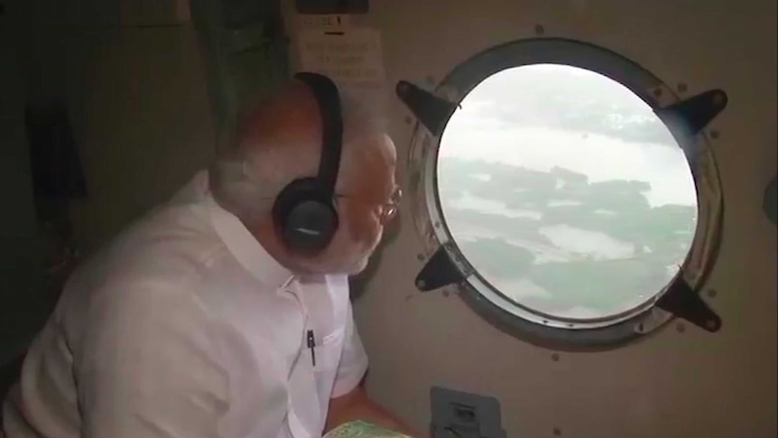 Indian Prime Minister Narendra Modi looks out from inside a helicopter to see flood