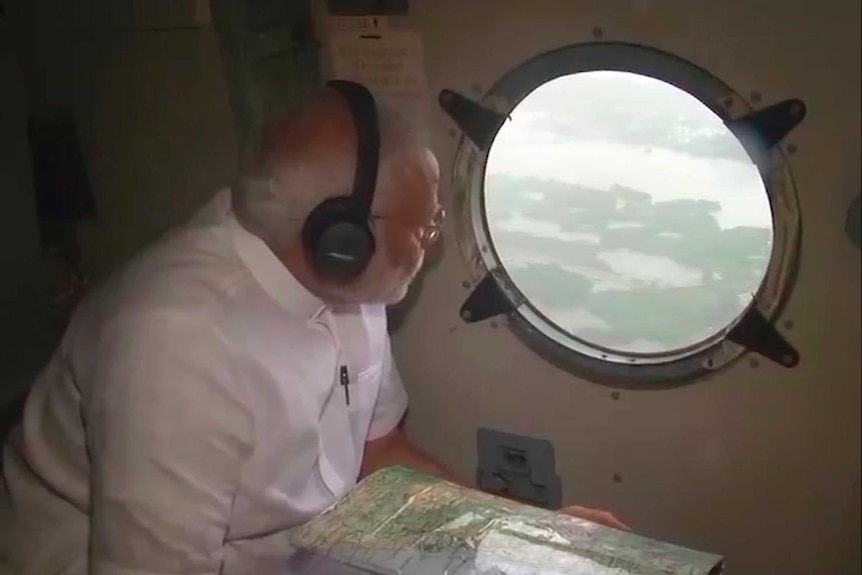 Indian Prime Minister Narendra Modi looks out from inside a helicopter to see flood
