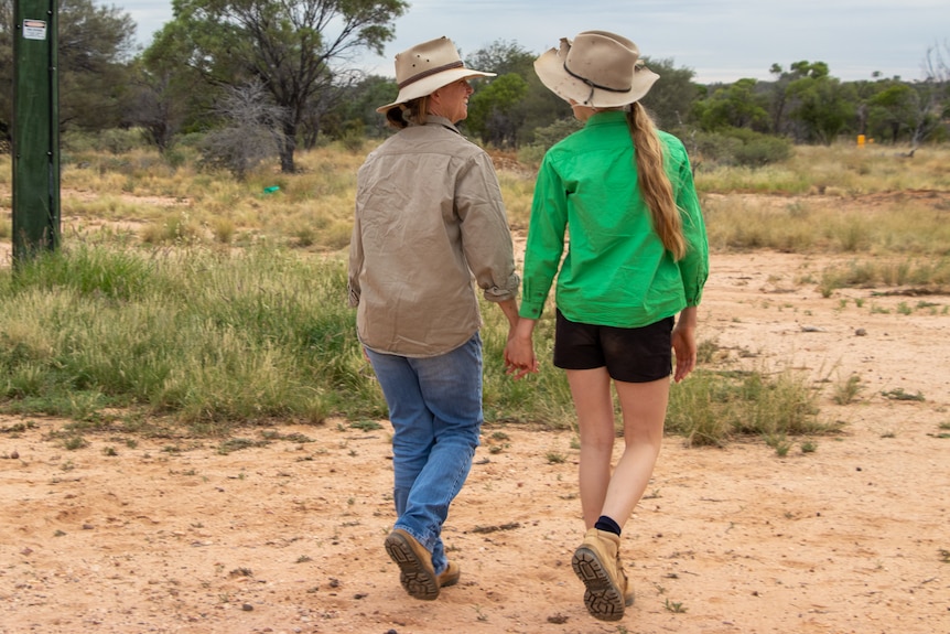 Rachael and her daughter Lucy walking holding hands on their property north of Longreach, November 2022. 